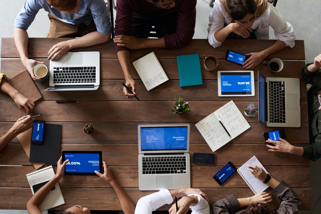 Gente trabajando en un escritorio, donde hay varios computadores