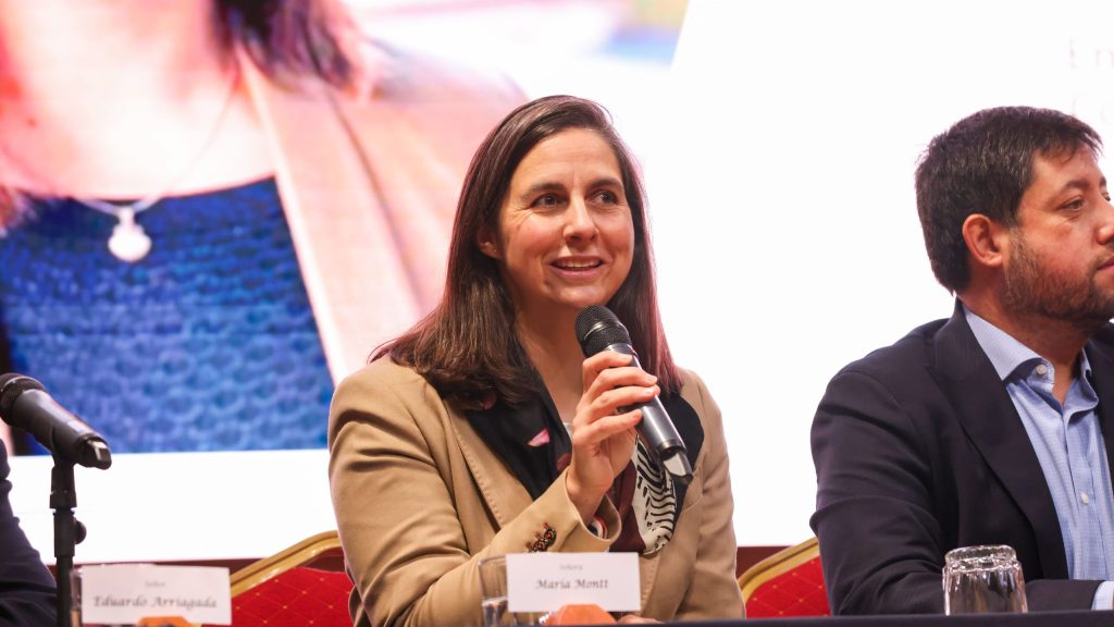 María Montt hablando en una conferencia con micrófono en mano.